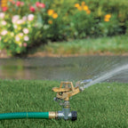 The Melnor 9535C Pulsating Sprinkler spiked into a green lawn watering the grass around it.