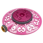 This image shows a pink and gray plastic rotating sprinkler with a decorative design, featuring a water inlet connection on its side.