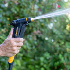 Melnor XT300 Front-Trigger Adjustable Nozzle with Flow Control turned to the jet setting in front of a blurred garden background.