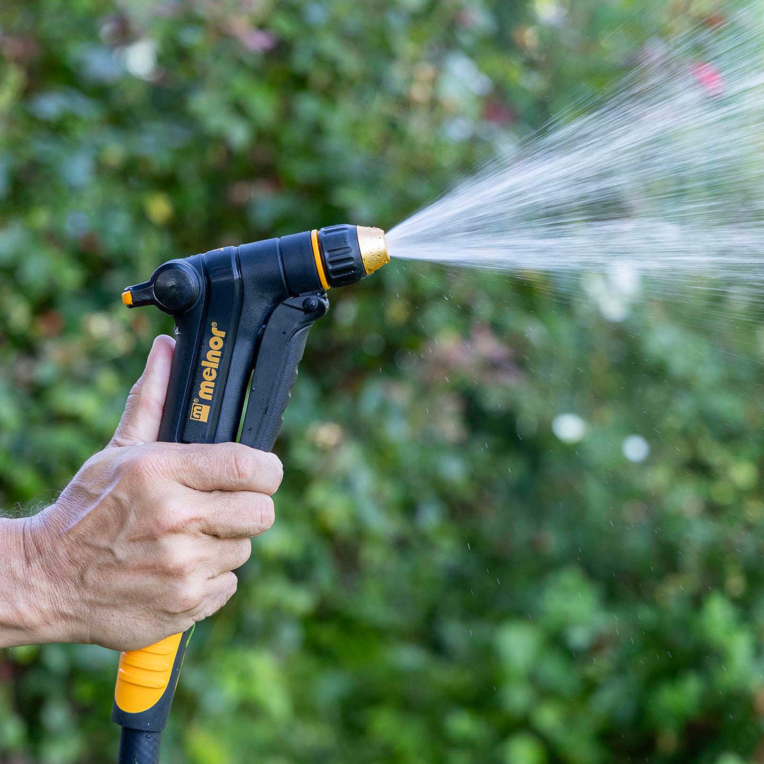Melnor XT300 Front-Trigger Adjustable Nozzle with Flow Control turned to the cone setting in front of a blurred garden background.