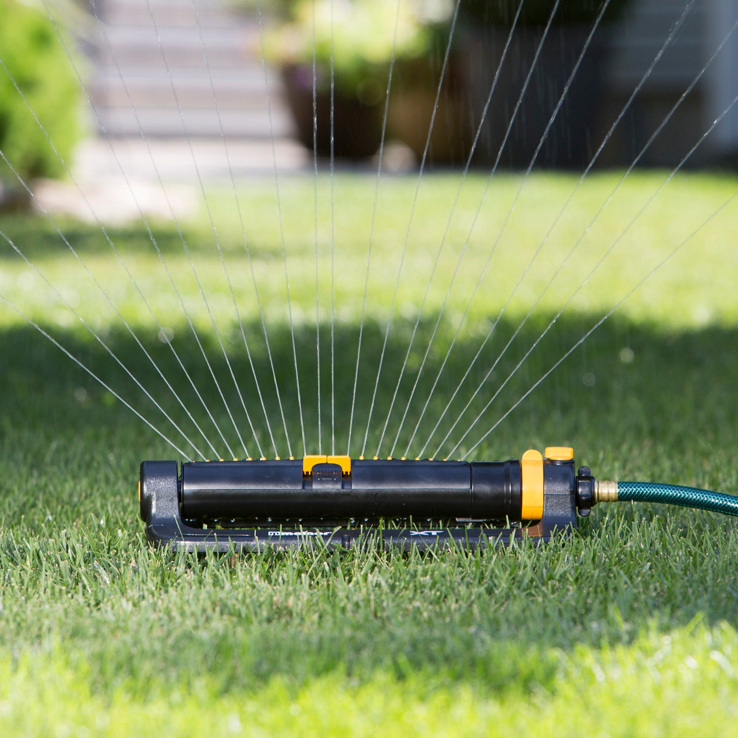 XT4200 Melnor XT 4,500 Sq. Ft. Turbo Oscillating Sprinkler with Flow Control gently spraying water over green lawn