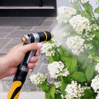 Person using the Melnor XT450 Heavyweight Metal Adjustable Nozzle to water white flowers.