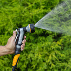 Hand holding the Melnor XT451 Heavyweight Metal 7-Pattern Nozzle in the Cone pattern against a green grass background.