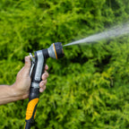 Hand holding the Melnor XT451 Heavyweight Metal 7-Pattern Nozzle in the Flat pattern against a green grass background.
