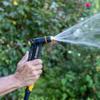 Melnor XT200 Rear-Trigger Adjustable Nozzle turned to the cone setting in front of a blurred garden background.