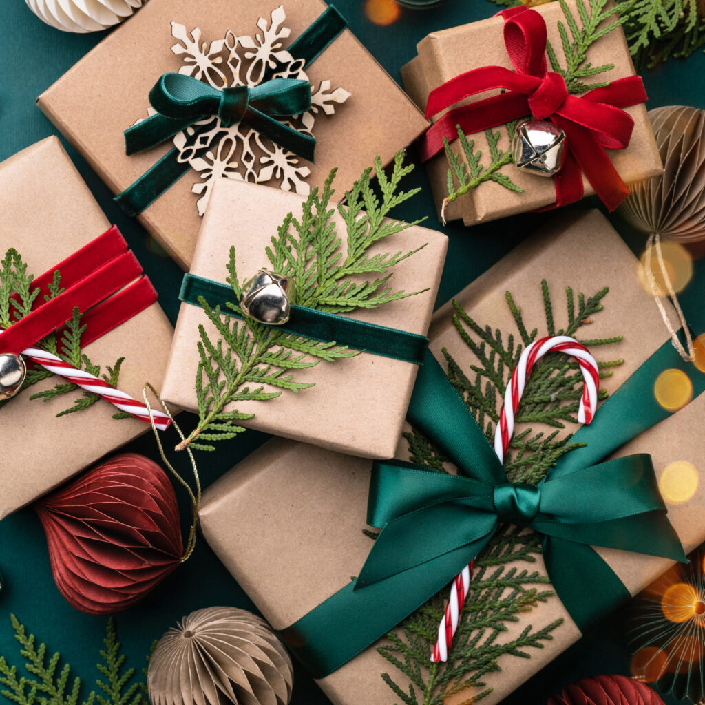 Gifts wrapped in natural kraft paper adorned with evergreen sprigs.