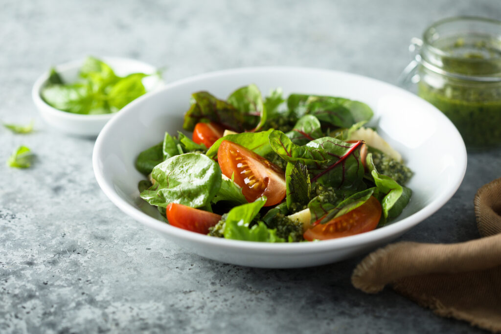 Bowl of fresh spinach salad with cherry tomatoes on a countertop.
